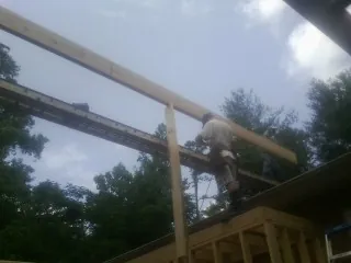 Carpenter setting a ridge beam over a new addition frame — Ice Dam Removal by Roofing Brothers in Lindenhurst