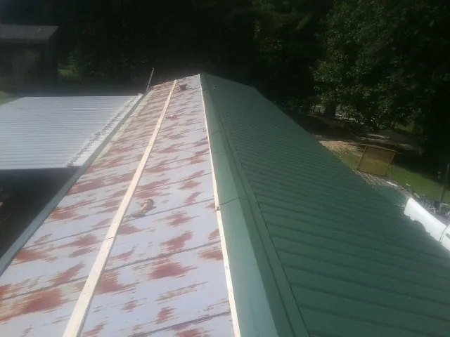 Old rusted panels beside newly installed green metal roofing — Wind Damage Roof Repair by Roofing Brothers in Lindenhurst