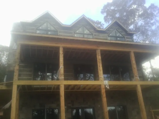 Dormers and porch framing on a large log home under construction — Roof Coating work by our crew in Lindenhurst