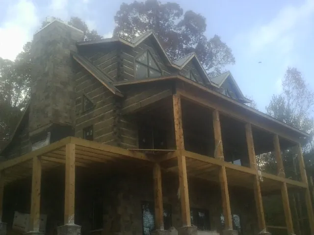 Stone chimney and dormers on a large log home with a timber porch in Lindenhurst