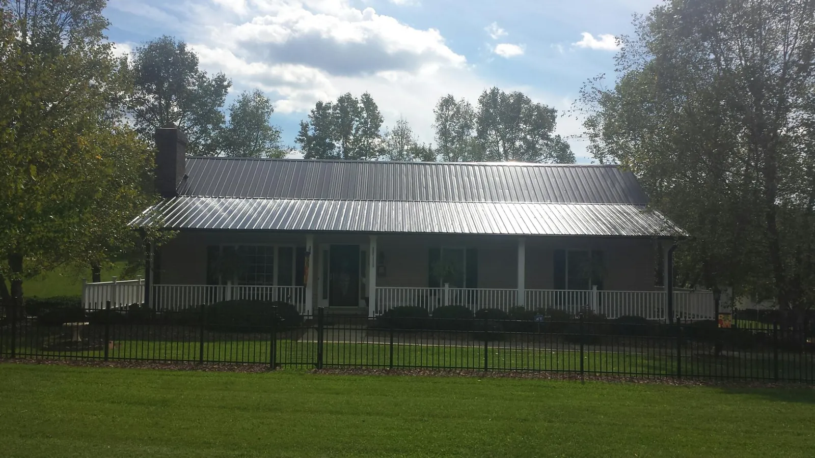 Gray metal roof on a brick ranch with a full width front porch — Gutter Guard Installation work by our crew in Lindenhurst