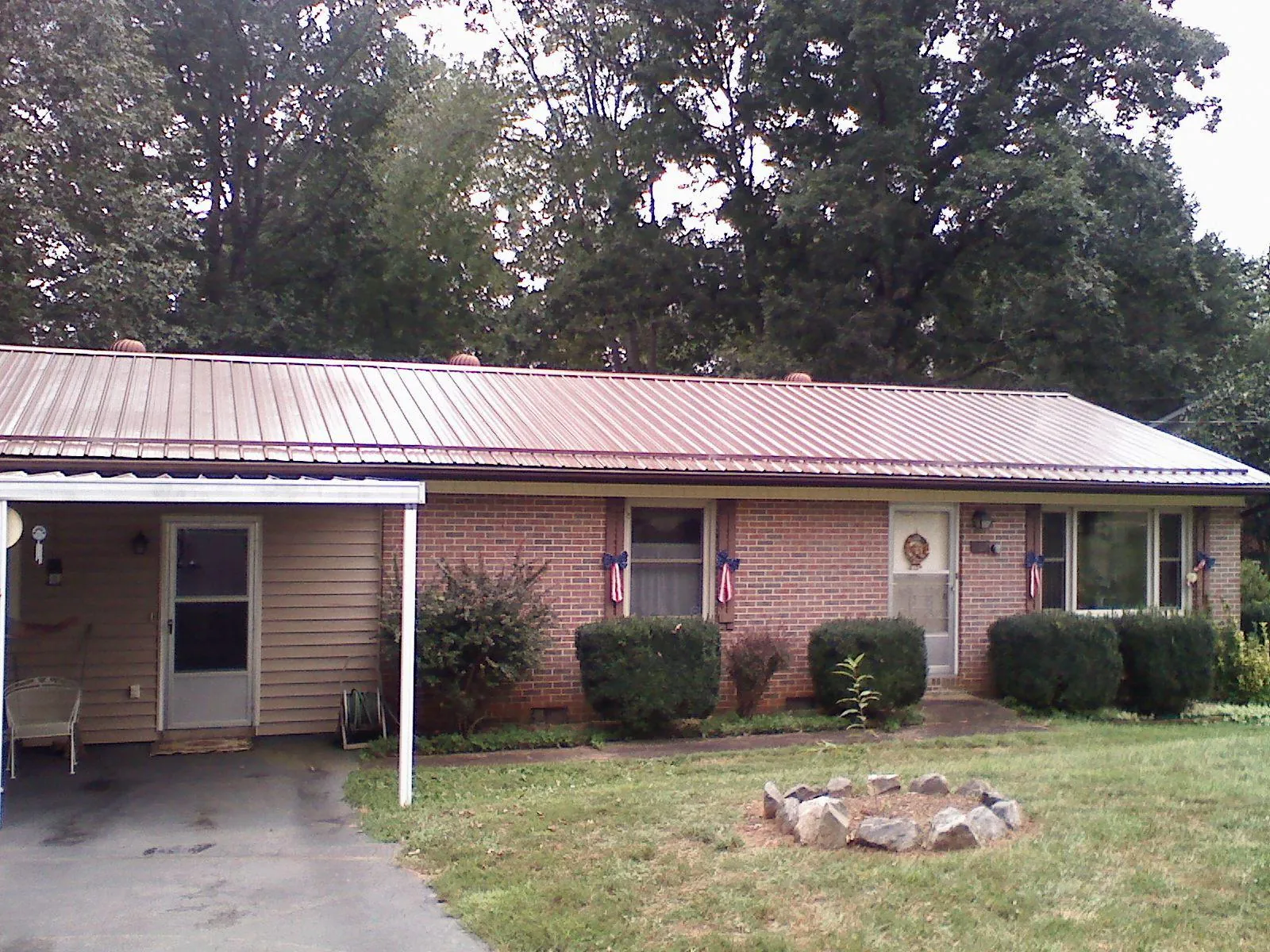 Bronze metal roof and carport on a brick ranch home — Roof Repair work by our crew in Lindenhurst