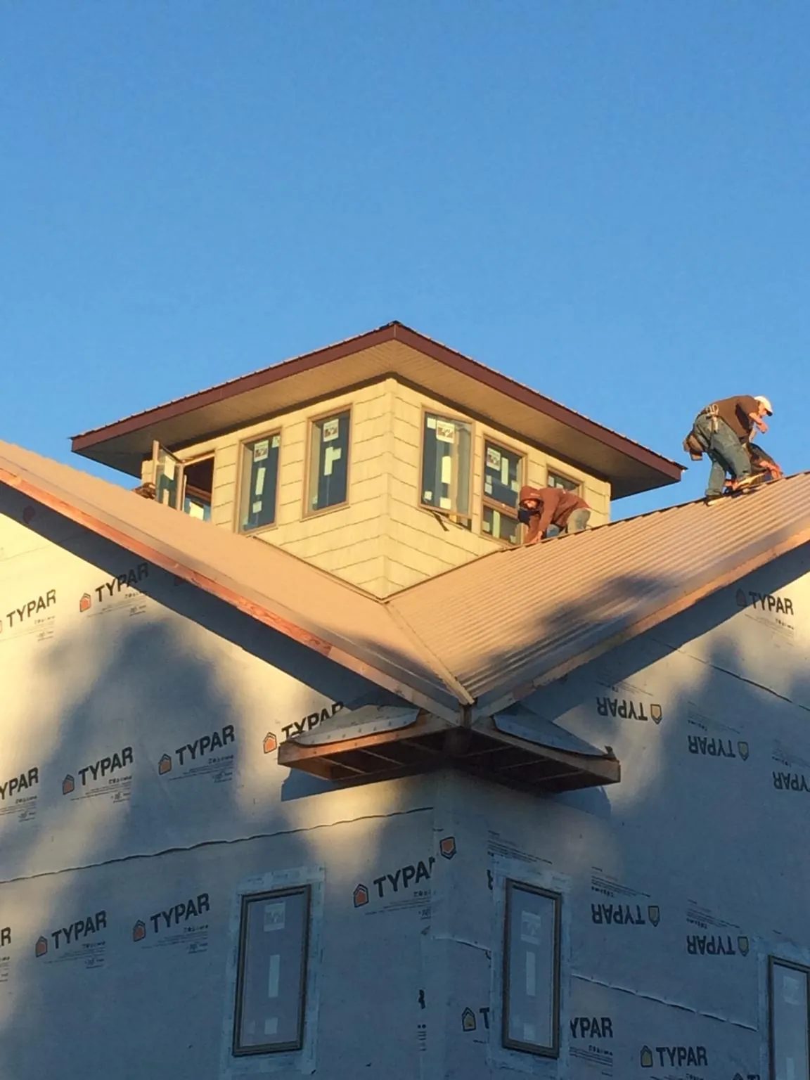 Roofers working around a rooftop cupola on a new metal roof at sunset — Roof Waterproofing in Lindenhurst by Roofing Brothers
